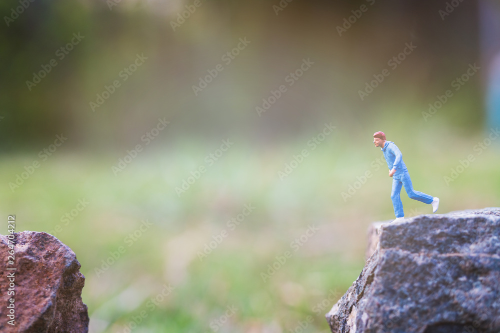 Miniature people : Running on rock cliff with nature background Miniature people : Running on rock cliff with nature background