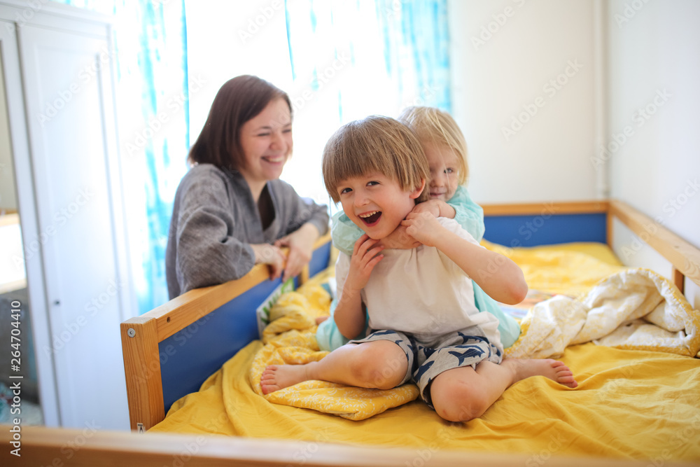 Siblings hugs with their mother on children's bed Siblings hugs with their mother on children's bed