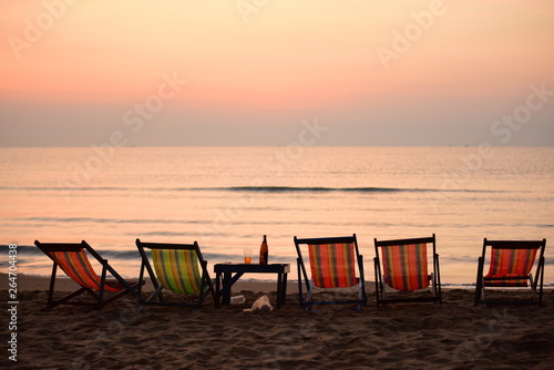 Early morning beach views With a lounge chair When the sun is rising Beautiful golden yellow sky and sun © tharathip
