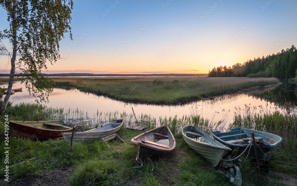 Beautiful sunset landscape with many row boats and peaceful lake at summer evening in Finland