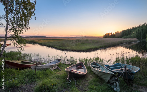 Beautiful sunset landscape with many row boats and peaceful lake at summer evening in Finland