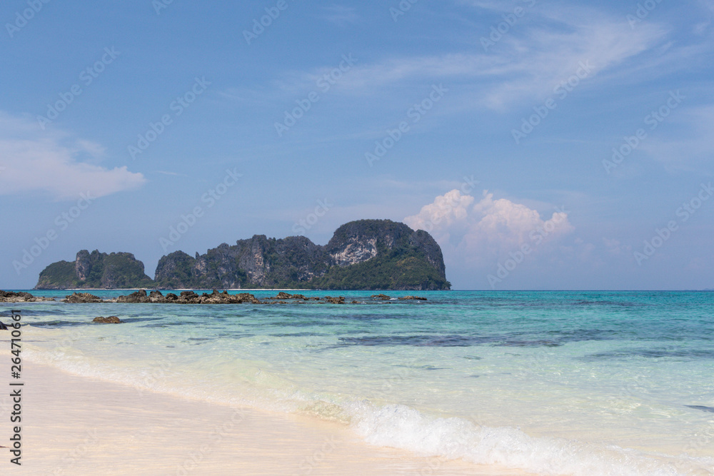 Fototapeta premium Blue sea and white sand with tropical mountains in the background