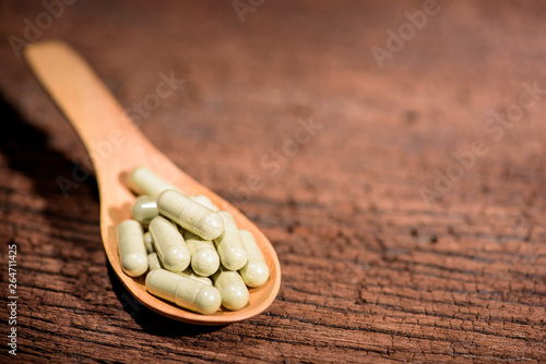herbal pills in wooden spoon