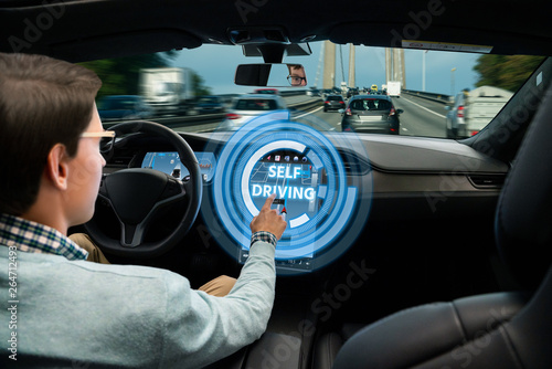 Man turns on autonomous driving mode in self driving car.