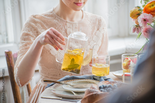 Tea time, Woman hands holding tea pot, flowers and cake