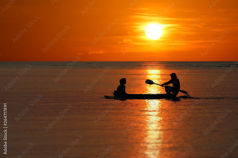 Silhouette of Local fishermen rowing small boats along the coast by the beach red sky sunset