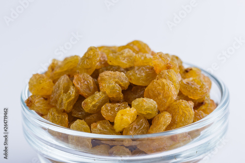 golden raisins on a white acrylic background