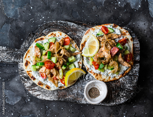 Greek chicken gyros flatbread on a rustic cutting board on a dark background, top view photo