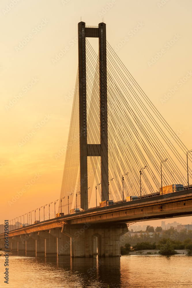 Obraz premium Row of trucks on Southern (Pivdennyi) bridge across Dnieper river at sunset, built in 1990 in Kiev, Ukraine