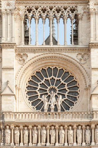 Close up of Notre Dame de Paris cathedral facade with rose window and row of stone statues in Paris, France