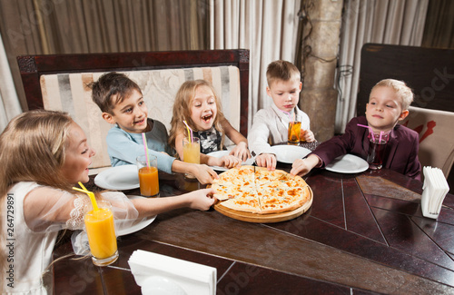 children eat pizza in a restaurant.