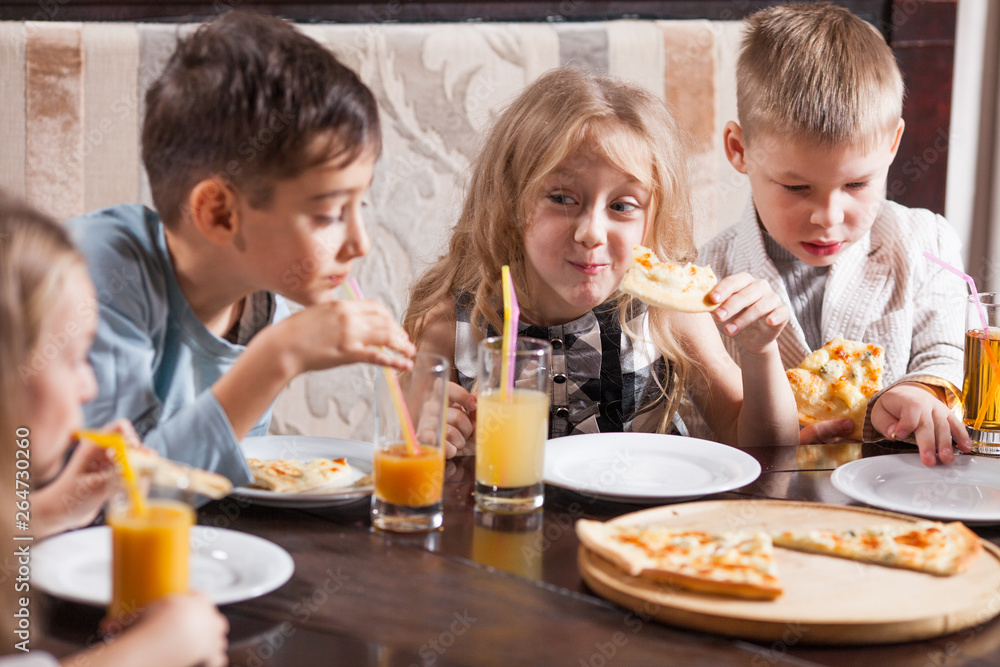 children eat pizza in a restaurant.
