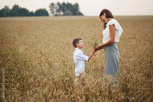 mother with son smiling holding hands in a field in summer. The concept of maternal love and tenderness, the relationship between parents and children