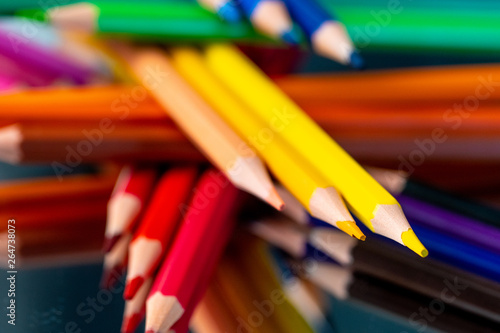 Many different colored pencils reflected on black