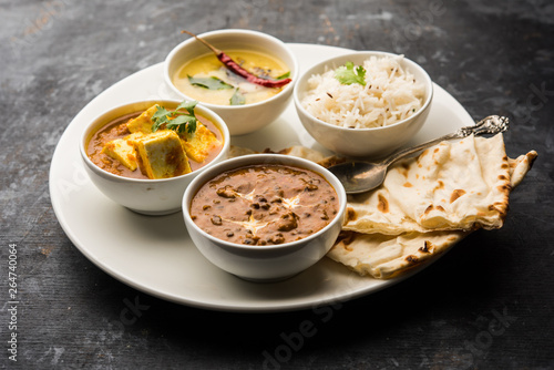 Indian vegetarian platter / Thali having Palak paneer butter masala, dal makhani, flat bread or naan and rice served in a white plate