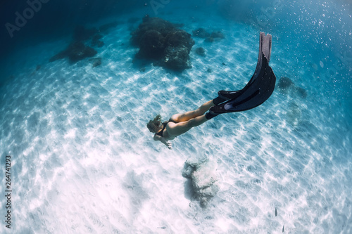 Woman freediver with sand over sandy sea with fins in Hawaii