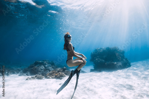 Woman freediver posing over sandy sea with fins. Freediving underwater in Hawaii