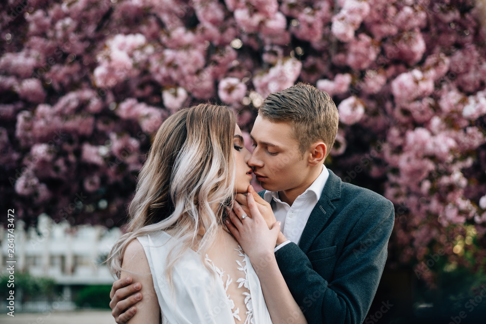 loving couple on the background of flowering trees, kiss loving couple on the background of flowering trees, kiss