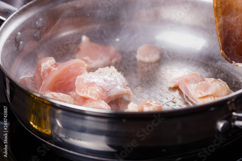 young woman in a gray aprons roasts chicken fillet with carrots