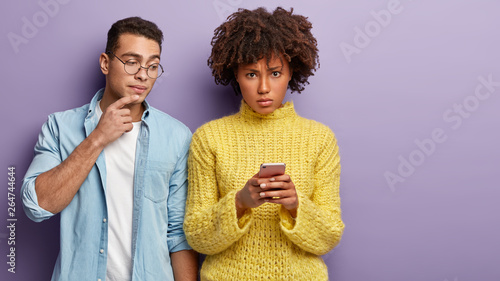 Fotografi Curious man peeps in cell phone of girlfriend