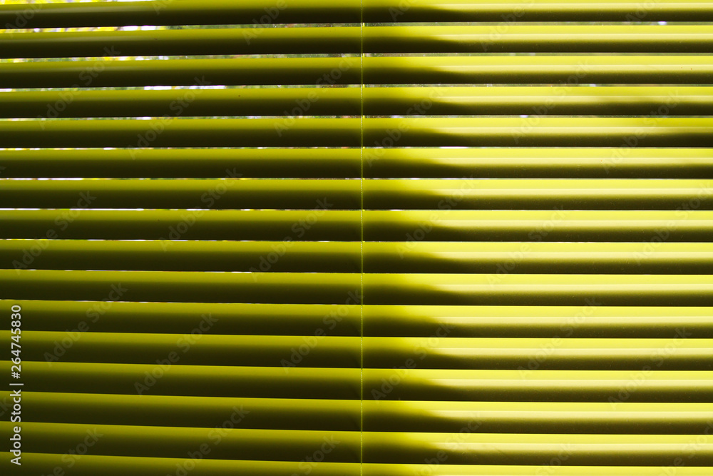 Obraz premium Yellow lamellas of vertical blind shining in natural sun light