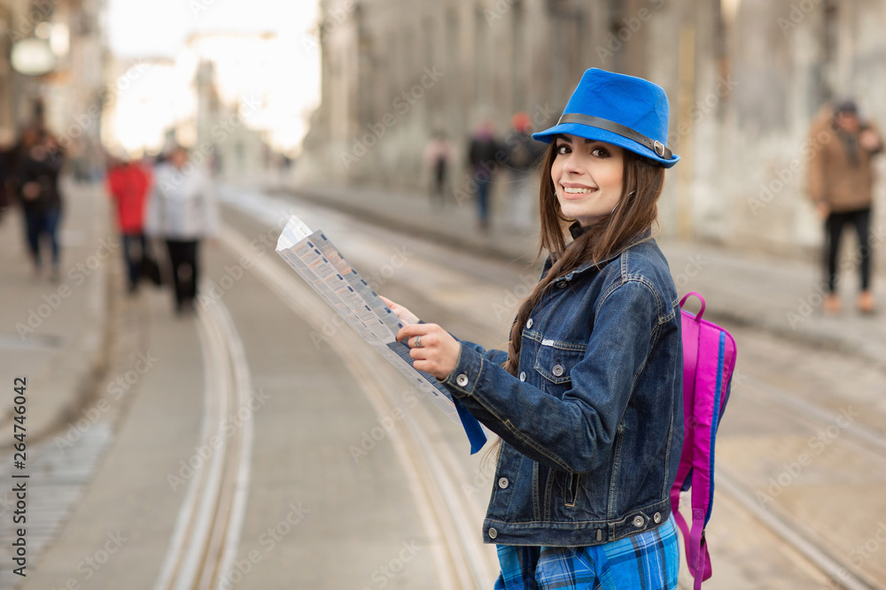 Young stylish woman walking on the old town street, travel with backpack and blue hat. Ukraine, Lviv Young stylish woman walking on the old town street, travel with backpack and blue hat. Ukraine, Lviv