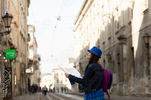 Young stylish woman walking on the old town street, travel with backpack and blue hat. Ukraine, Lviv