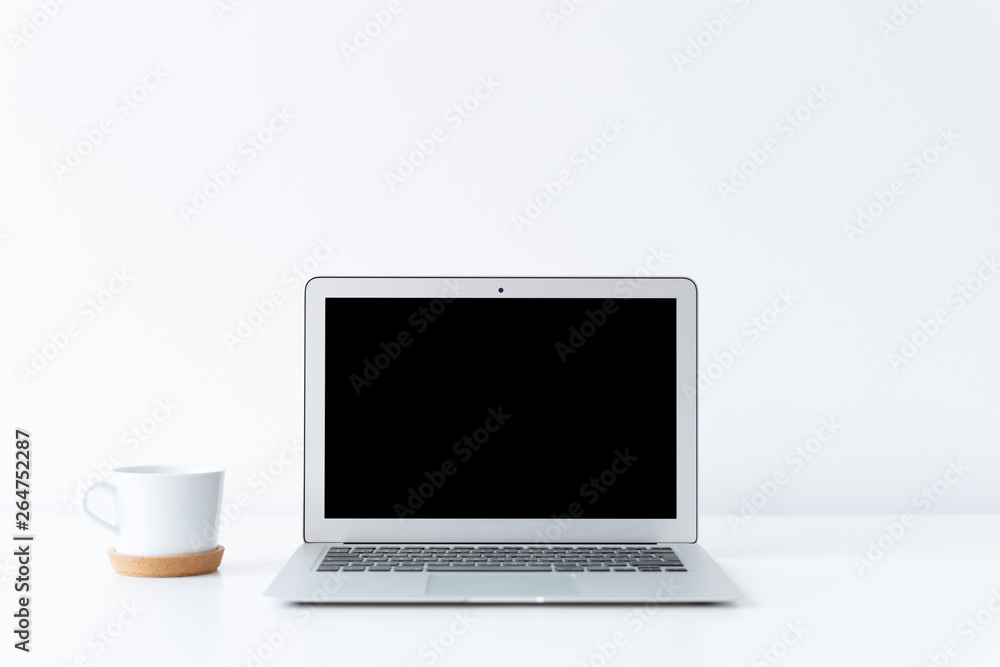 Open laptop and cup of coffee or tea on the desk with white background Open laptop and cup of coffee or tea on the desk with white background