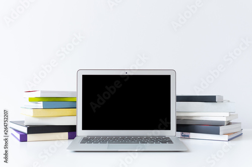 Open laptop and colourful books on the desk with white background
