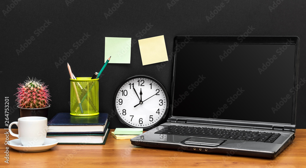 Laptop with clock, office supplies and cup of coffee at the work place. Front view. Laptop with clock, office supplies and cup of coffee at the work place. Front view.