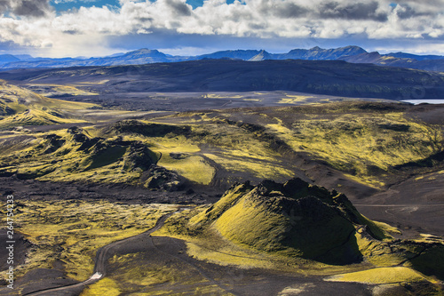 Dramatic iceland landscape of Craters of Laki volcanic fissure with a green hill and black lava looks like a moon.