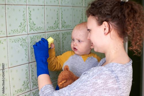 A mother with her little son is cleaning the house. The concept of combining homework and raising a child. photo