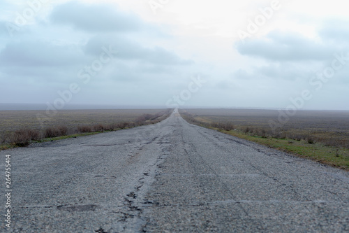 Wide old road in the foggy steppe