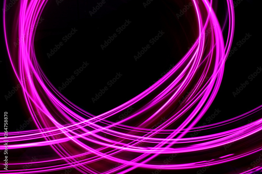 Fototapeta premium Long exposure, light painting photography. Vibrant neon pink loops and streaks of colour against a black background