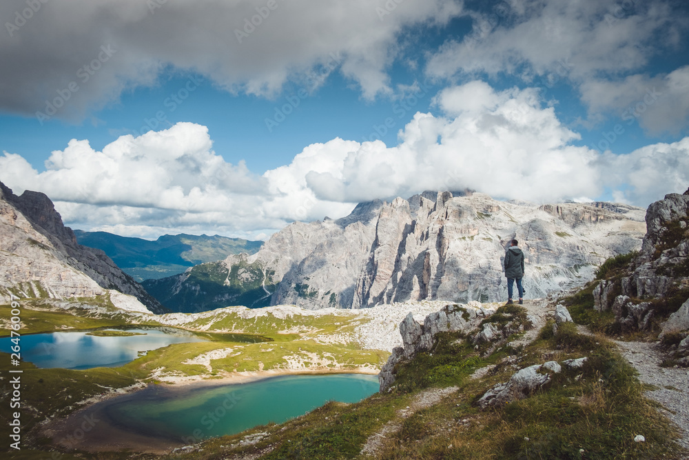 Fotograf turysta stoi na skale nad górskimi jeziorami Tre Cime di Lavaredo w słoneczny dzień