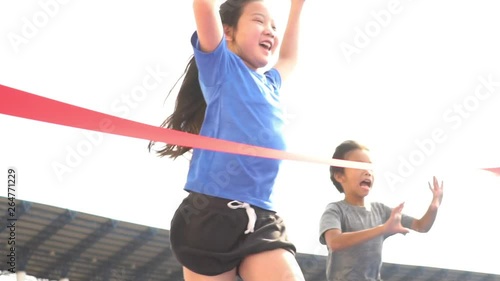 Slow motion of young Asian boy and girl run through a finish line