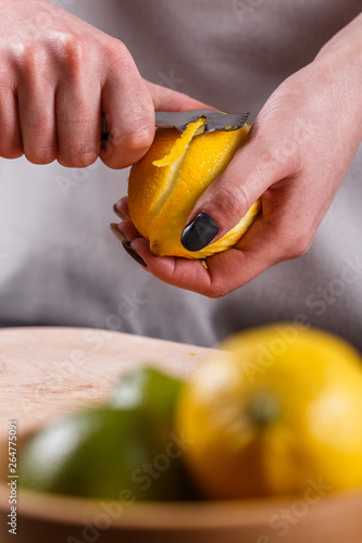 young woman in a gray aprons cuts lemon zest