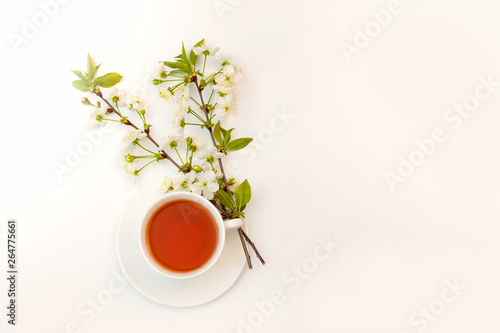 cup with tea and a blooming twig of cherry