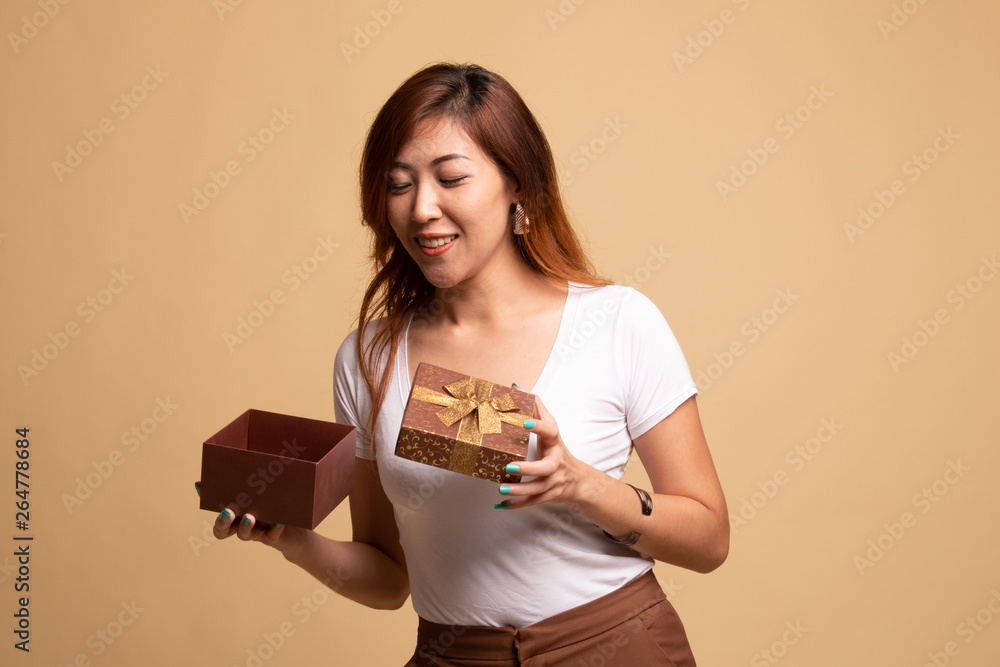 Young Asian woman open a golden gift box. Young Asian woman open a golden gift box.