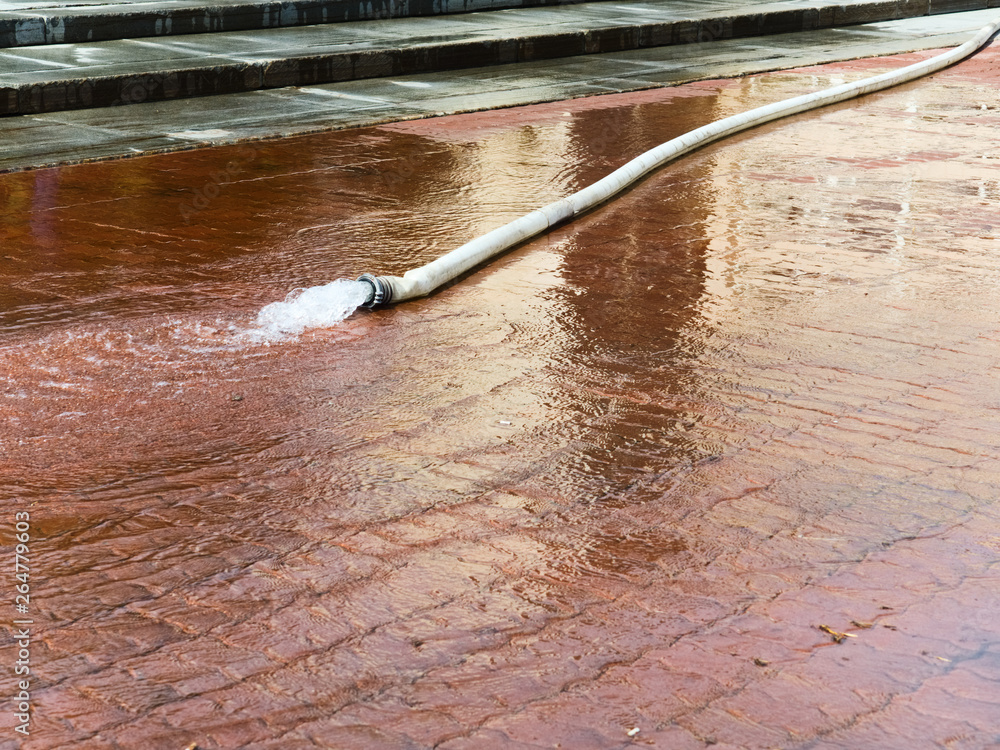 water is poured onto the sidewalk from a disconnected fire hose water is poured onto the sidewalk from a disconnected fire hose