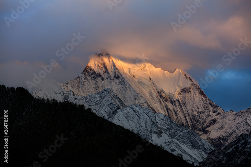 Chenadorje, holy snow mountain in Daocheng Yading Nature Reserve - Garze, Kham Tibetan Pilgrimage region of Sichuan Province China. Cliffs, Glaciers, Ice and Snow Mountain Summit View. Glowing Sunset