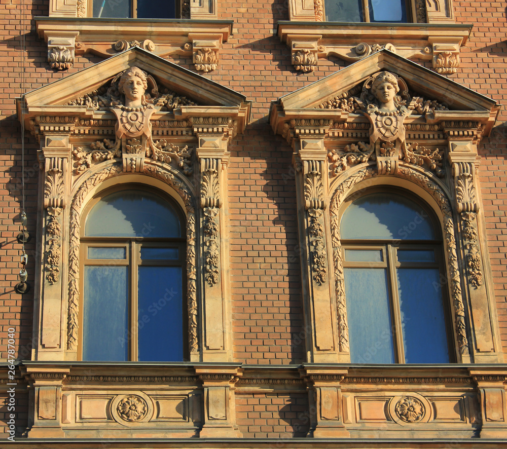 Obraz premium Two ornamental windows on classical house facade. Arched windows on building exterior walls with decorative elements
