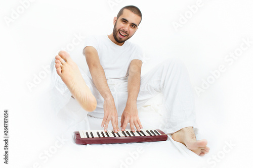 Happy young man playing an musical instrument barefeet with withe background