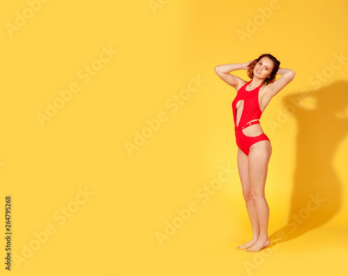 beautiful girl in red swimsuit on yellow background