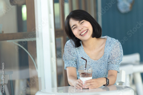 young asian woman short hair in sky dress holding a cup of ice frappe chocolate   young woman smiling