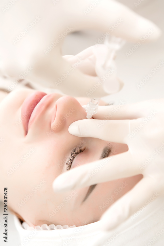 Naklejka premium a girl in a white sterile hat is lying on a couch by a beautician and she is given injections to smooth out wrinkles around the eyes