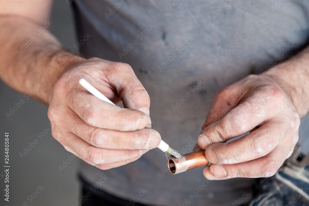 Closeup worker plumber master cleaning copper pipes with professional brush. Concept installation, changing pipeline, solder flux paste, repair, leakage, break Closeup worker plumber master cleaning copper pipes with professional brush. Concept installation, changing pipeline, solder flux paste, repair, leakage, break