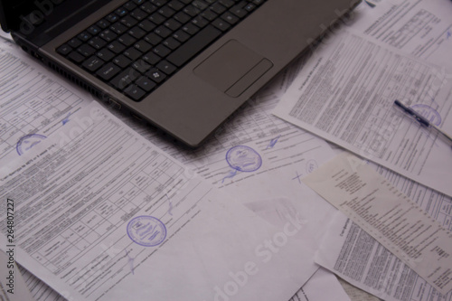 Office Desk with papers, receipts and documents. Work with documents at the plant or enterprise. Laptop or computer on the office Desk with documents. Job.