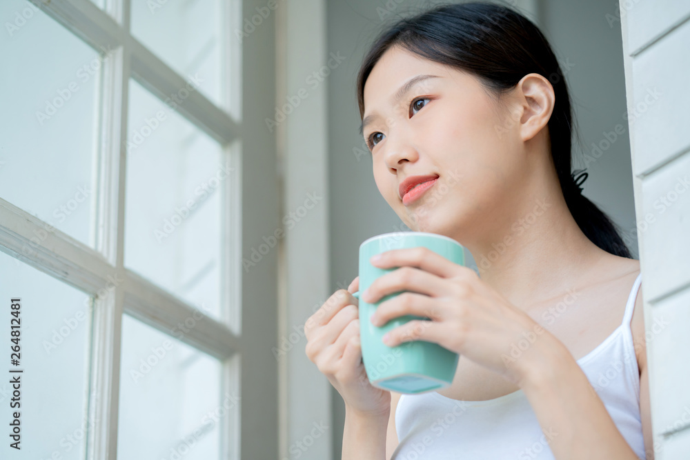 beautiful asian teen white Tank top happiness smile enjoy freshness morning with hot drink near window with sun light beautiful asian teen white Tank top happiness smile enjoy freshness morning with hot drink near window with sun light
