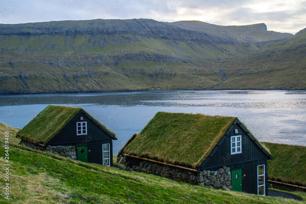 Traditional nordic Scandinavian village houses with green grass roof. Iconic scenic view of Faroe Island, Denmark, Europe. Beautiful tourist spot located at Vágar Island. Moody weather scene. Traditional nordic Scandinavian village houses with green grass roof. Iconic scenic view of Faroe Island, Denmark, Europe. Beautiful tourist spot located at Vágar Island. Moody weather scene.